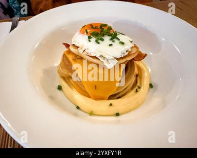 Salziger Pfannkuchen mit Ei, Cheddar-Käsesauce und Speck, serviert im Restaurant. Bereit zum Essen Stockfoto