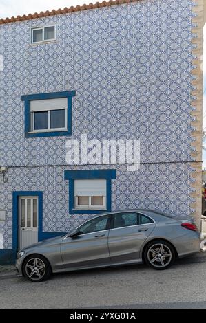 Costa Nova, Portugal - 11. September 2024 : Silbernes Auto parkt in der Nähe eines blau-weiß gekachelten Hauses in einer malerischen Nachbarschaft Stockfoto