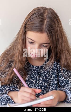 Ein trauriges Mädchen zieht ein Notizbuch ein. Die Hausaufgaben zu Hause. Stockfoto