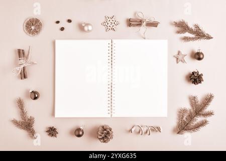 Bei der Vorlage handelt es sich um einen sauberen, offenen Notizblock mit einem Platz für Text auf beigefarbenem Hintergrund mit verschiedenen natürlichen Dekorationen für Weihnachten. Flache Draufsicht, ein Plac Stockfoto