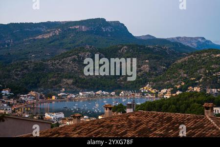 Abendlicher Port de Soller. An den Lichtern der gemütlichen Cafés und Restaurants am Meer. Boote und Yachten bewegen sich in der Nähe des Ufers. Die schmale Bucht ist von mou umgeben Stockfoto