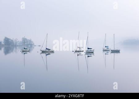 Bootsreihe mit ruhigen Reflexen im Wasser in Waterhead, Windermere, Lake District, Großbritannien. Stockfoto