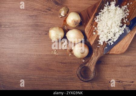 Fein gehackte Zwiebeln auf einem Schneidebrett mit einem Messer, Holztisch, Draufsicht, keine Leute Stockfoto