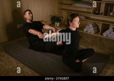 Ein männlicher Massagetherapeut führt eine Rückenmassage zur Schmerzbehandlung im Spa durch. Thai-Massage mit Masseur im Spa. Stockfoto