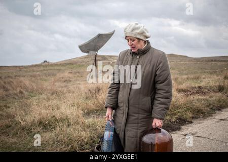 Frau mit Trinkwasser nach Hause, im Hintergrund Gedenkstätte Kertsch-Eltigen Operation im Zweiten Weltkrieg, Kertsch, Krim, Ukraine, Europa Stockfoto