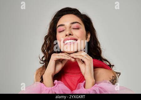 Die schöne junge Frau zeigt ihren verspielten Geist mit einem strahlenden Lächeln und farbenfrohem Make-up. Stockfoto