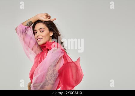 Eine junge, schöne Frau zeigt ihre verspielte Seite, während sie ein farbenfrohes Outfit in einem Studio trägt. Stockfoto