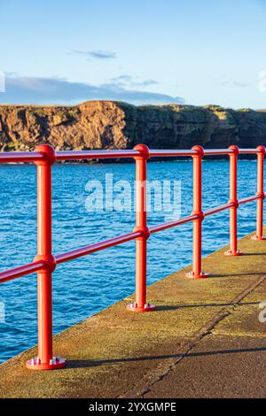 Glänzende neue rote Geländer am West Pier im Hafen von Eyemouth, Berwickshire, Scottish Borders, Schottland, Großbritannien Stockfoto