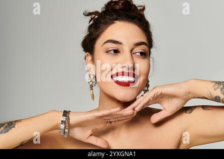 Die schöne junge Frau zeigt ihr strahlendes Lächeln und ihren stilvollen Schmuck, während sie elegant posiert. Stockfoto