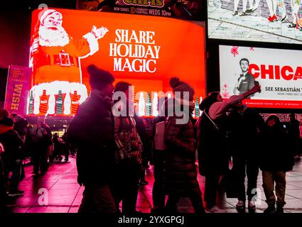 Besucher des Times Square in New York am Mittwoch, den 4. Dezember 2024, spazieren unter mehreren digitalen Plakatwänden mit Weihnachtsmotiven, die Coca-Cola Werbung machen. (© Richard B. Levine) Stockfoto