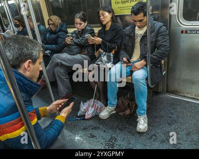 Abgelenkte Reisende in der New Yorker U-Bahn am Mittwoch, den 11. Dezember 2024. (© Richard B. Levine) Stockfoto