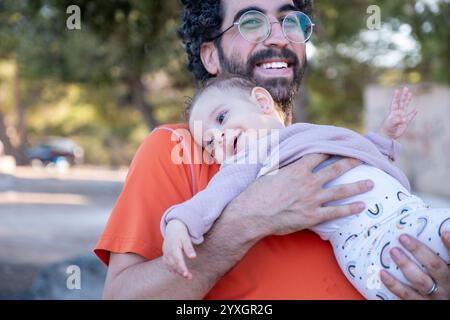 Ein fröhlicher Vater wirft seine kleine Tochter während eines sonnigen Familienausflugs hoch in die Luft und feiert Liebe, Verspieltheit und die kostbare Bindung der Eltern Stockfoto