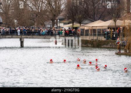 Thun, Schweiz - 8. Dezember 2024: Die Weihnachtsklauseln tauchen in das kalte Wasser des Flusses Aare bei einer jährlichen Veranstaltung während der Weihnachtsmarktsaison Stockfoto