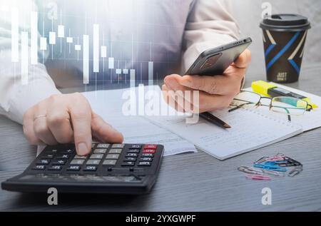 Kostenberechnung und Analyse von Finanzdaten in einem professionellen Arbeitsbereich mit Notizen und Unterlagen in der Nähe als Referenz. Stockfoto