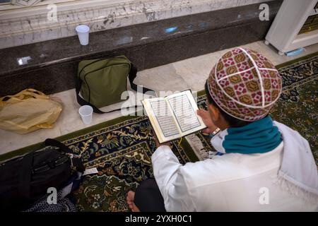 Mekka, Saudi-Arabien - 4. Juni 2024: Ein indonesischer Mann, Hajj und Umrah Pilger sitzend und lesend Quran in Masjidil Haram, große Moschee in Makkah, Sa Stockfoto