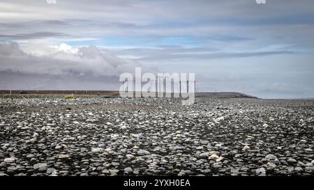 Stromleitungen durchqueren eine riesige felsige Ebene in island unter bewölktem Himmel Stockfoto