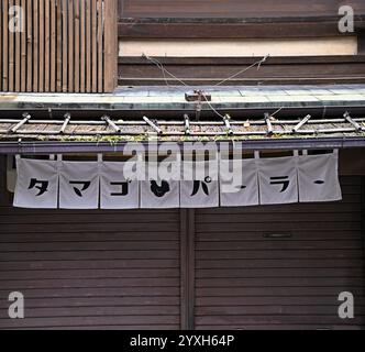 Traditionelles japanisches kurzes Noren-Vorhangpaneel am Eingang eines lokalen Ladengeschäfts mit Holzfassade in Kyoto, Japan. Stockfoto