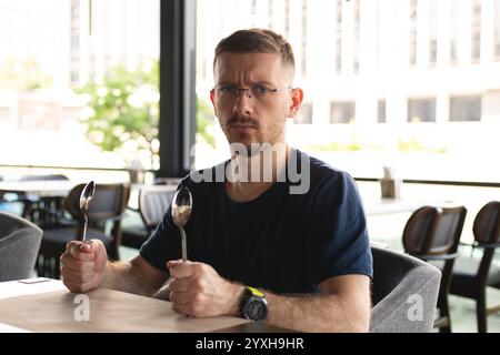 Hungriger junger Mann in einem Café Stockfoto