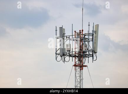 Antennenmast für drahtlose Kommunikation, Antennenmast für Mobiltelefone auf dem Dach eines baufälligen Gebäudes Stockfoto