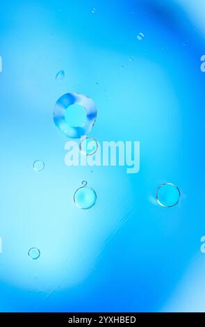 Minimalistisches abstraktes Bild mit Wasserblasen, die vor einem leuchtend blauen Farbverlauf schweben. Perfekt für Designs, die Kopierraum und einen benötigen Stockfoto