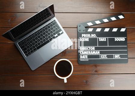 Filmklatscher, Laptop und Kaffee auf Holztisch, flache Ladefläche Stockfoto