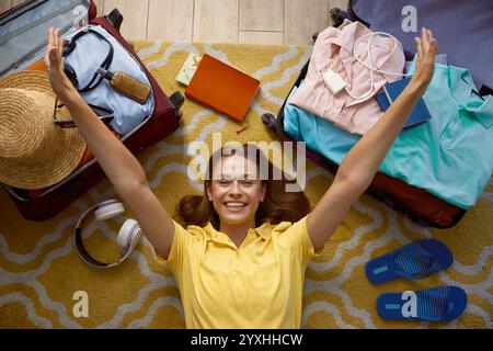 Zufriedene, aufgeregte Frau, die auf dem Boden liegt und sich über die Startzeit für den Urlaub freut Stockfoto