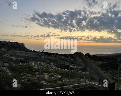 Ein atemberaubender Sonnenuntergang über den Hügeln der Küste in der Nähe von Ayia Napa, Zypern, schafft eine ruhige und malerische Landschaft. Der Himmel ist in leuchtenden Farben von ora gemalt Stockfoto