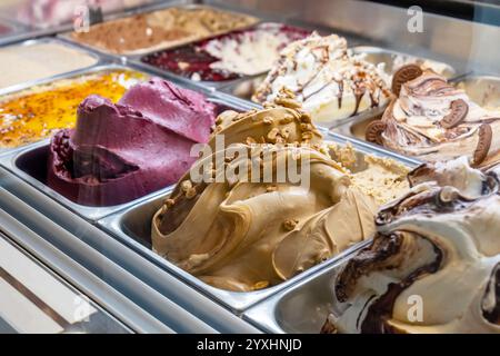 Verschiedene Feinschmecker-Craft-Eis-Aromen in einem Ladencafé-Vitrine, cremige Texturen mit Karamell-Nüssen Schokolade, Beere sorb Stockfoto