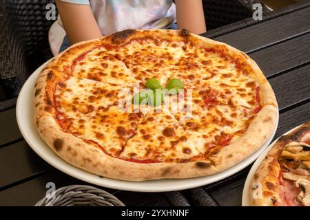 Klassische Margherita Pizza ohne zusätzliche Beläge auf dem Tisch serviert in einem Restaurant, Pizzeria, Nahaufnahme dicke Schicht geschmolzenen Käse, hoch und Stockfoto