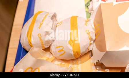 Zwei McDonald's Cheeseburger in Papierverpackungen auf einem Tablett, Fast Food-Artikel mit Branding in Nahaufnahme, Fast-Food-Artikel mit Schnellkäse-Burger-Mahlzeit in Nahaufnahme, Burger mit Stockfoto