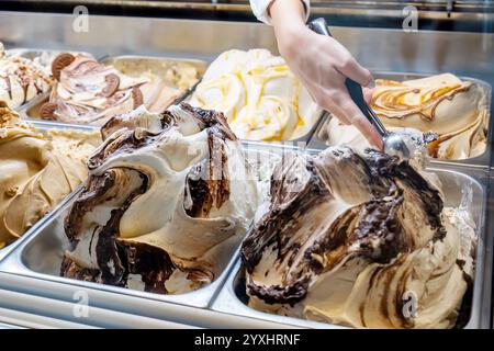 Cremiges Vanille- und Schokoladeneis, serviert mit einem Löffel aus einer Vitrine mit mehreren Geschmacksrichtungen in einem Dessertgeschäft, einem Foodtruck-Eisstadion Stockfoto