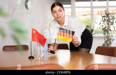 Vorbereitung auf Geschäftsverhandlungen - Frau setzt kleine Flaggen von Ländern Chinas und Deutschlands auf den Tisch Stockfoto