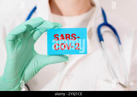 Die Hände des Arztes in blauen Handschuhen mit weißem Papier und Text 'BA.2,86 Pirola Variant'. Konzept für die neue Variante von SARS-CoV-2 BA.2,86 Pirola COVID- Stockfoto