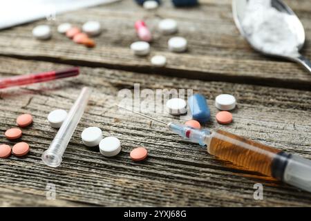 Drogensucht. Spritze und Pillen auf Holztisch, Nahaufnahme Stockfoto