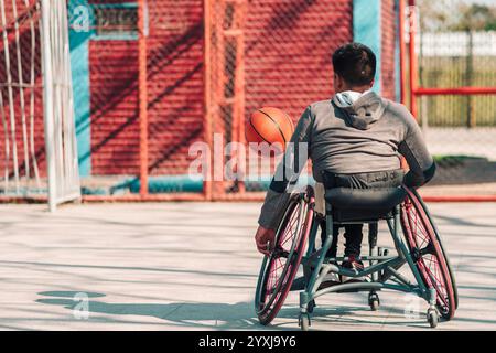 Junger Latino-Athlet im Rollstuhl, Training, Spiel und Konzentration mit Basketball in einem Stadtpark im Freien Stockfoto