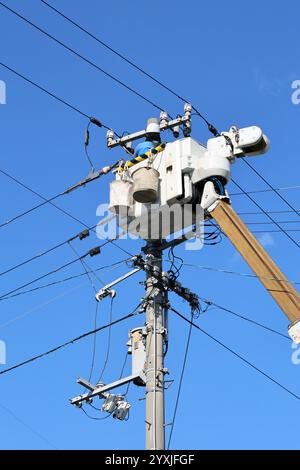 Kagawa, Japan - 12. Dezember 2024: Elektriker Techniker mit Schutzhelm und Sicherheitsuniform überprüfen die Reparatur von elektrischen Kabeln am Strommasten. Spannung Pow Stockfoto