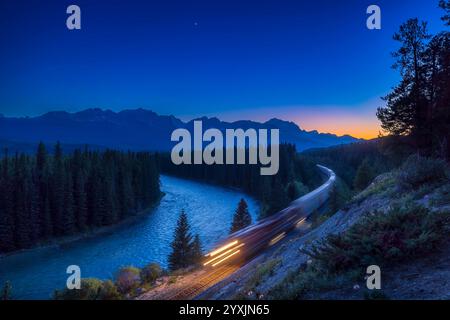 Güterzug, der in der Abenddämmerung durch die Kanadischen Rocky Mountains fährt, mit der hellen Venus am Himmel. Stockfoto