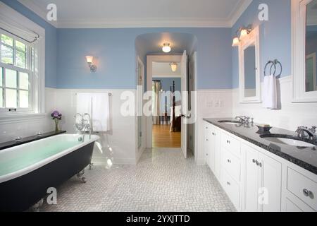 Blaues Badezimmer mit Badewanne und Schlafzimmer durch die Tür Stockfoto