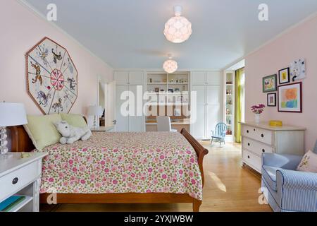 Rosafarbenes Mädchen-Schlafzimmer mit integriertem Schreibtisch, Schränken und Regalen Stockfoto