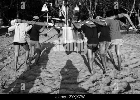 Fischer arbeiten zusammen, um ihre Boote von der Küste zu heben, nachdem sie vom Fischen am Papuma Beach zurückgekehrt sind. Stockfoto