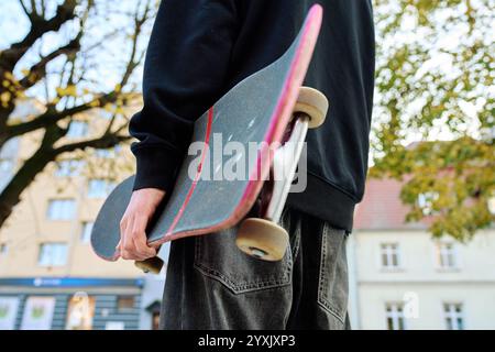 Skateboarder in Baggy-Jeans mit kratzenden Skateboardern auf der City Street. Der Teenager ist Skateboarding. Konzept der Jugendsubkultur Stockfoto