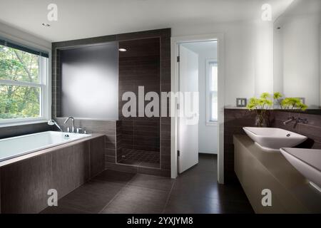 Modernes Bad mit großem grauen Fliesenboden, Badewanne und ebenerdiger Dusche Stockfoto