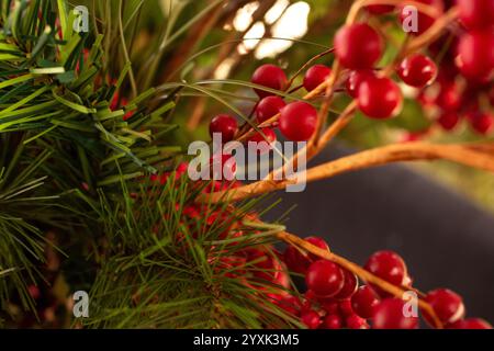 Eine Nahaufnahme einer falschen Pflanze aus Kiefernnadeln, Kiefernzapfen und roten Beeren. Stockfoto