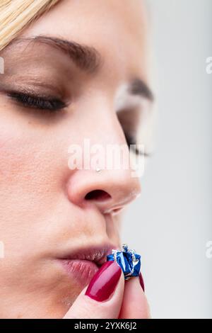 Ein kleines geliebtes Geschenk bekommt einen Kuss von einer verschwommenen Frau im Hintergrund. Der Gedanke hinter dem Geschenk ist ihr wichtig Stockfoto