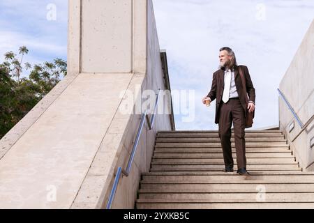 Reifer Geschäftsmann, der die Treppe hinunter läuft Stockfoto