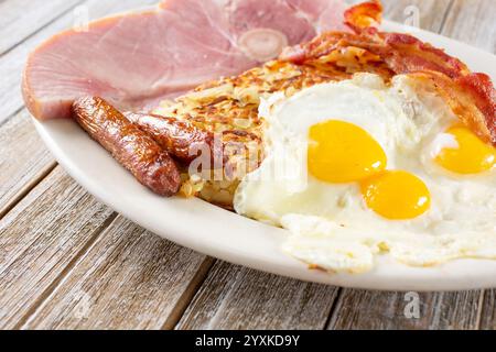 Blick auf einen Frühstücksteller mit sonnigen Eiern, Würstchen, Kartoffelröstchen, Speck und Schinken. Stockfoto
