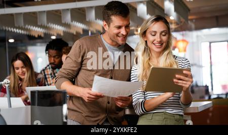 Lächelnd treffen sich verschiedene Kollegen in einem Brainstorming in der Vorstandsetage, um gemeinsam Finanzstatistiken zu diskutieren Stockfoto