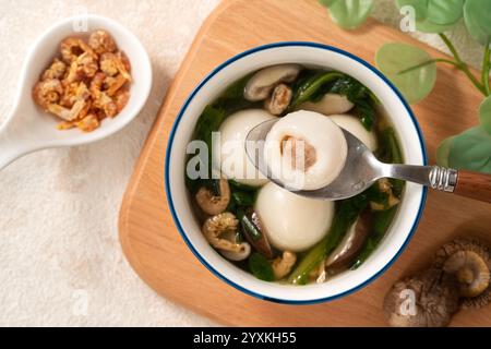 Essen Sie große Tangyuan Yuanxiao, Tang Yuan, klebrige Reisknödelbällchen, mit herzhafter Gemüsesuppe in einer Schüssel für das Wintersonnenfest. Stockfoto