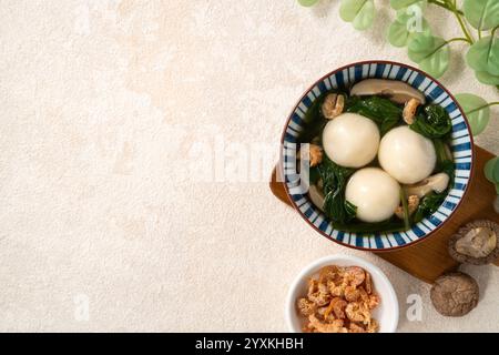 Essen Sie große Tangyuan Yuanxiao, Tang Yuan, klebrige Reisknödelbällchen, mit herzhafter Gemüsesuppe in einer Schüssel für das Wintersonnenfest. Stockfoto