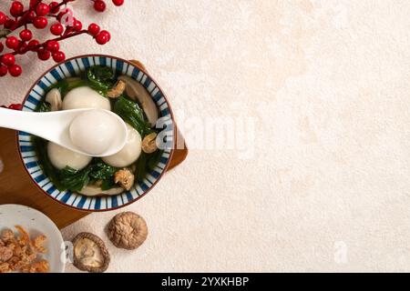 Essen Sie große Tangyuan Yuanxiao, Tang Yuan, klebrige Reisknödelbällchen, mit herzhafter Gemüsesuppe in einer Schüssel für das Wintersonnenfest. Stockfoto